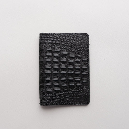 Black crocodile-embossed leather passport cover on a light background