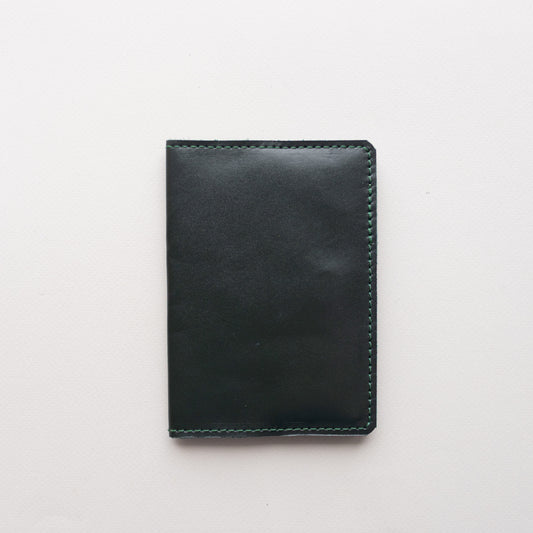 Dark green smooth leather passport cover Doco closed on a light background