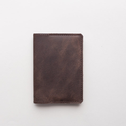 Closed chocolate brown vintage-effect leather passport cover on a white background
