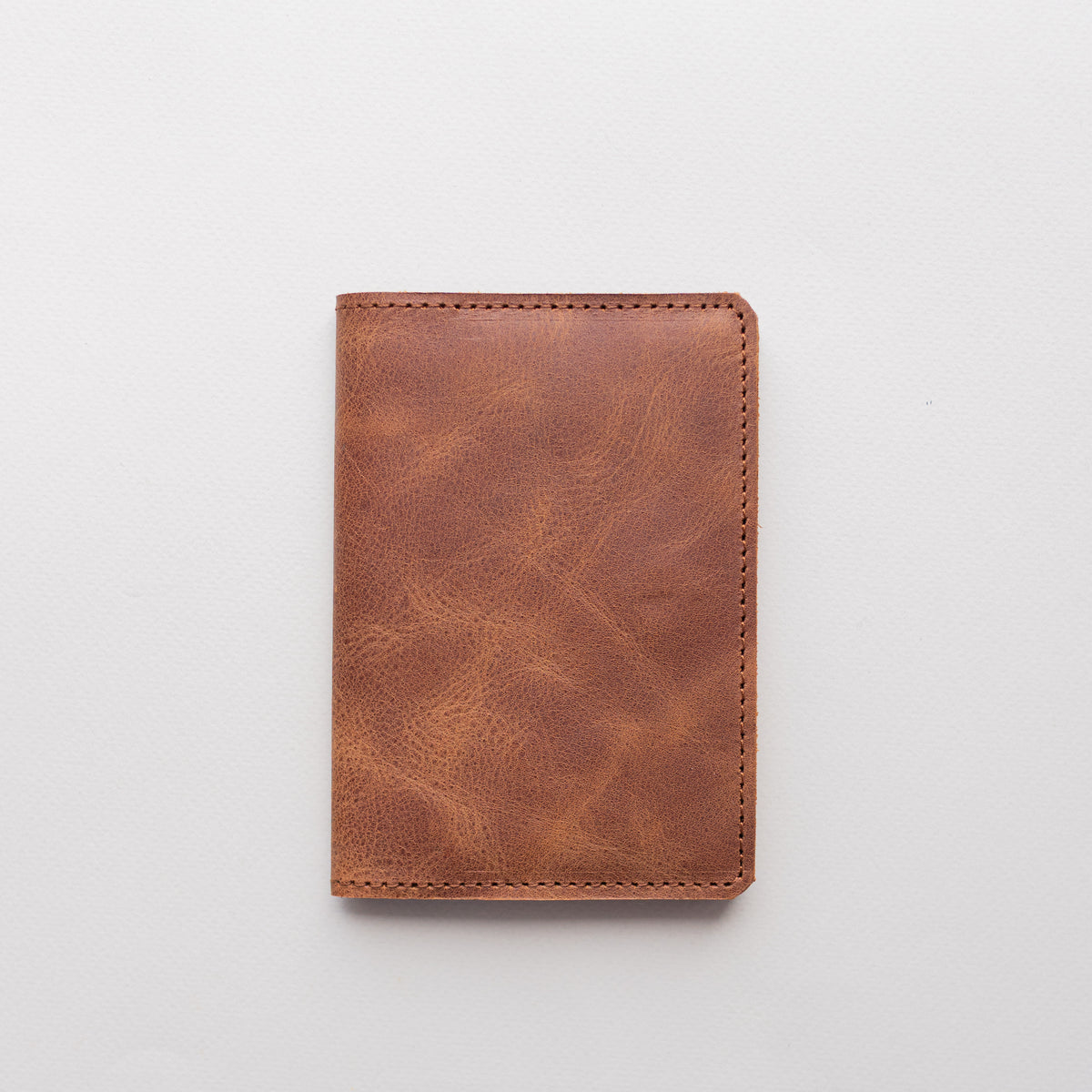 Closed whiskey brown vintage-effect leather passport cover on a white background