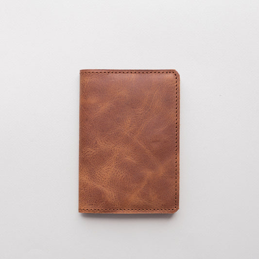 Closed whiskey brown vintage-effect leather passport cover on a white background
