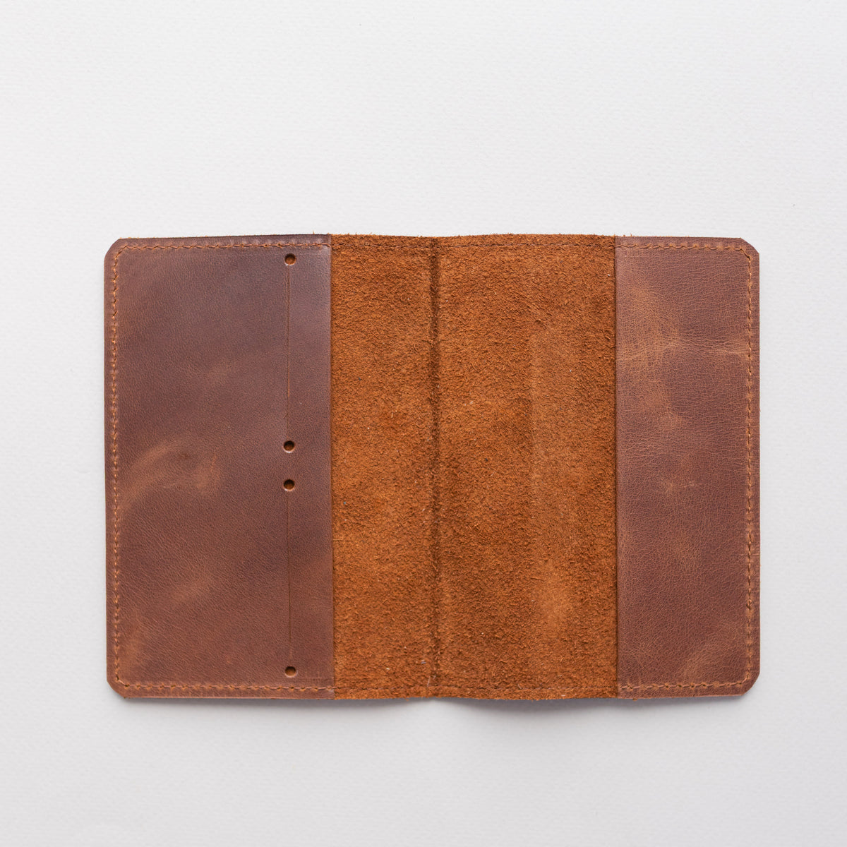 Open whiskey brown leather passport cover laid flat showing the inside