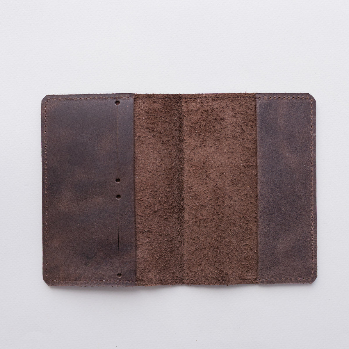 Open chocolate brown leather passport cover laid flat showing the inside