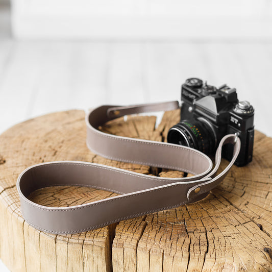Cappuccino leather camera strap Fix with a vintage film camera on a wooden stump